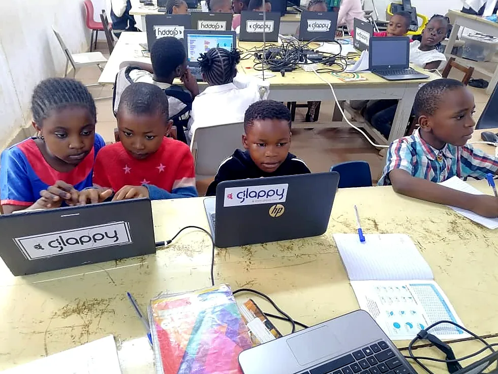 Young students sit in a row at Glappy laptops, ready for the day's lesson